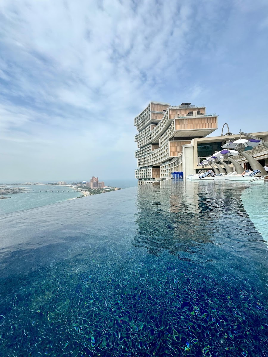 Aerial view of Dubai rooftop infinity pool at sunset with city skyline and Arabian Gulf coastline