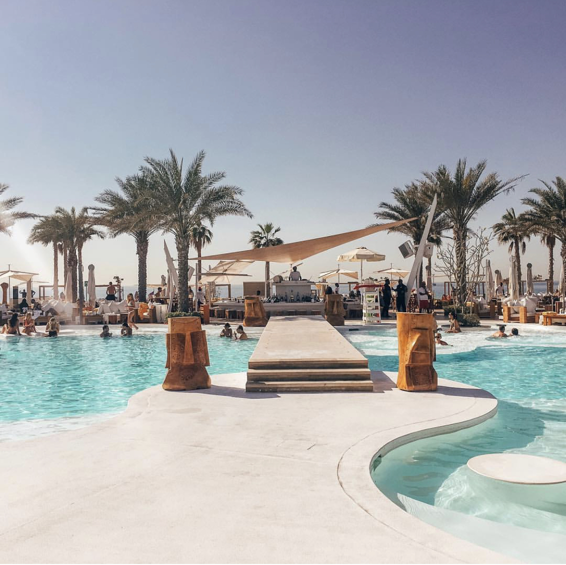 Nikki Beach Dubai — white sunbeds and palm trees at the iconic global beach club brand on Pearl Jumeira