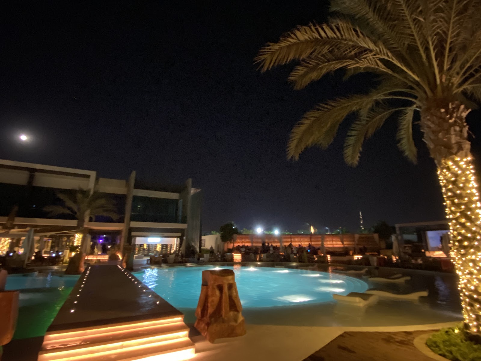 Nikki Beach Dubai — pool with white sunbeds, palm trees and golden umbrellas at Pearl Jumeirah